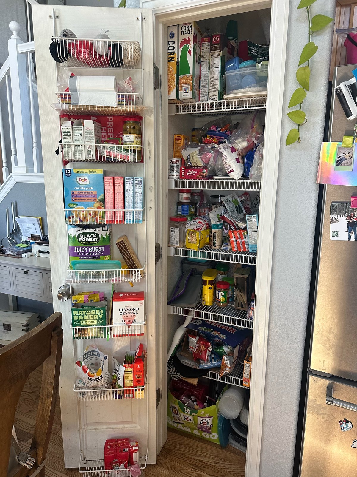 Organized kitchen pantry shelving with wire baskets and bins storing snacks, beverages, and household items