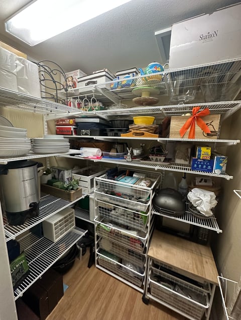Organized kitchen pantry shelves filled with cookware, appliances, storage containers, and household items
